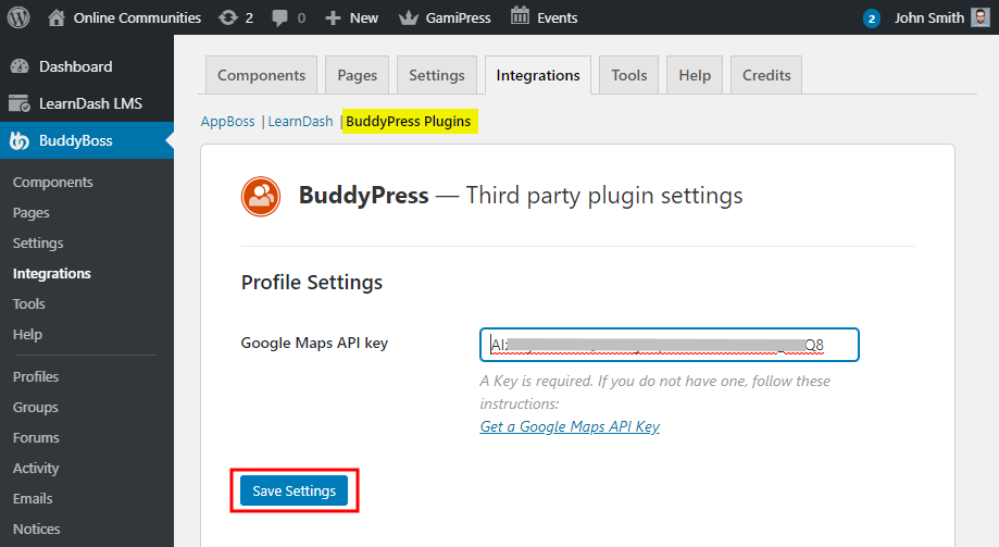 A screenshot of a WordPress admin page shows the BuddyPress plugins Profile Settings. A Google Maps API key field is filled, and a blue Save Settings button is highlighted with a red box.
